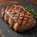 12 oz USDA Choice New York strip steak with grill marks on dark slate board