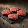 Four 1/4-pound 80/20 beef burger patties on a dark slate board