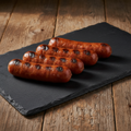 Three all-beef smoked hot dogs with grill marks on a dark slate board
