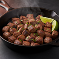 Seasoned carne asada sizzling on a cast iron skillet with cilantro and lime